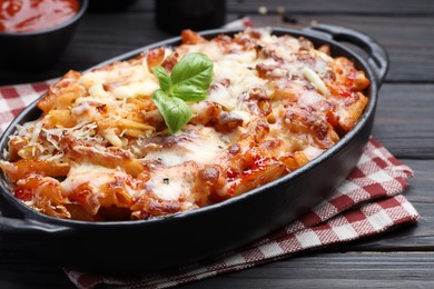 Photo of Delicious al forno pasta in baking dish on wooden table, closeup