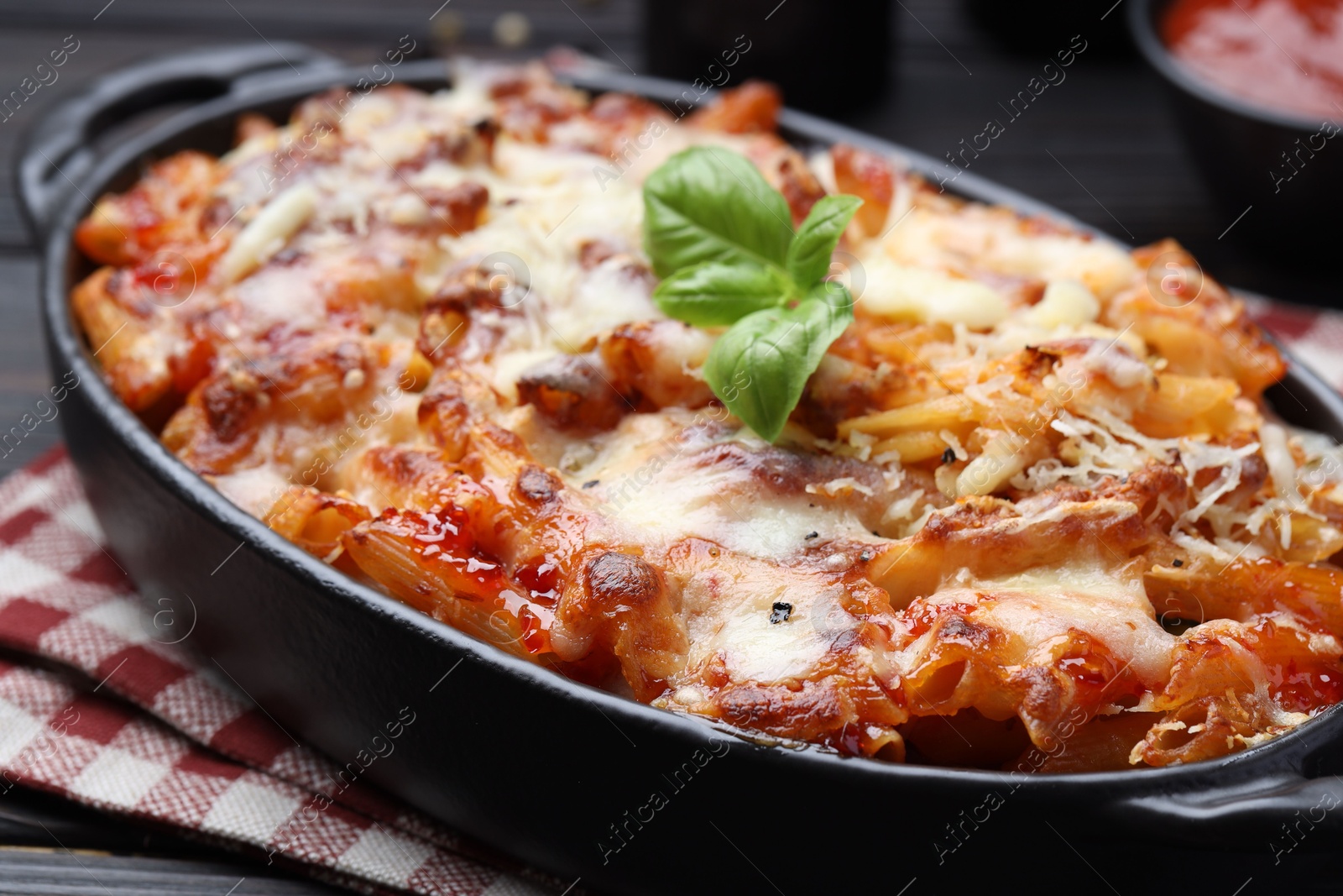 Photo of Delicious al forno pasta in baking dish on wooden table, closeup