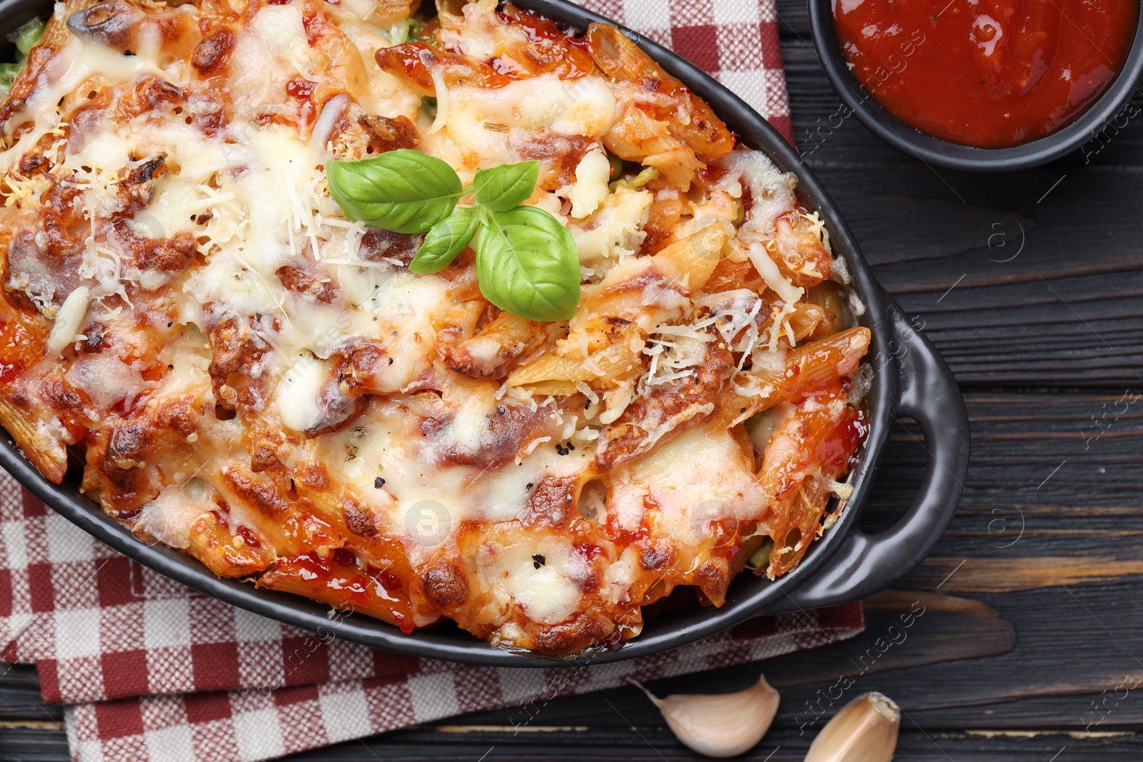 Photo of Delicious al forno pasta in baking dish on wooden table, flat lay