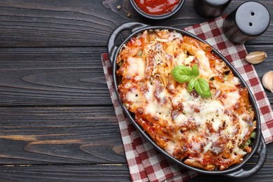 Photo of Delicious al forno pasta in baking dish on wooden table, flat lay. Space for text