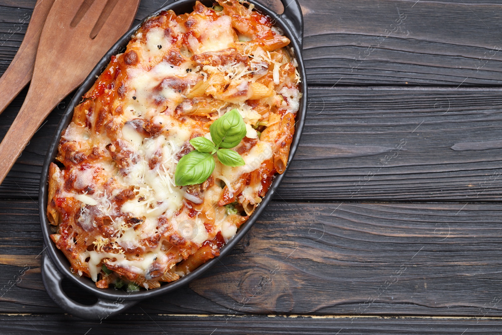 Photo of Delicious al forno pasta in baking dish on wooden table, top view. Space for text