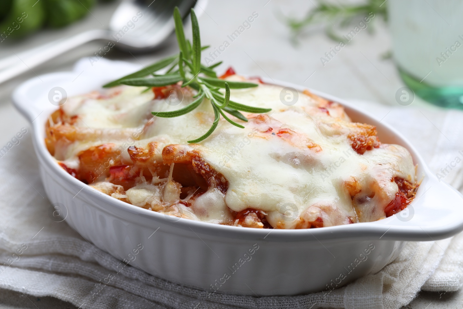 Photo of Delicious al forno pasta in baking dish on light table, closeup