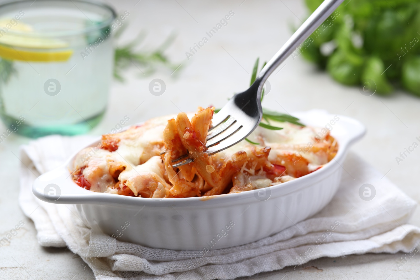 Photo of Eating delicious al forno pasta at light table, closeup