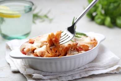 Photo of Eating delicious al forno pasta at light table, closeup