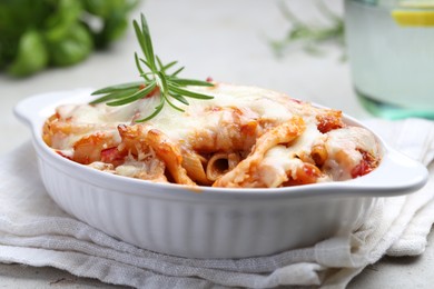 Photo of Delicious al forno pasta in baking dish on light table, closeup