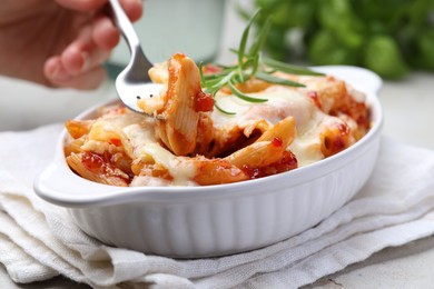 Photo of Woman eating delicious al forno pasta at light table, closeup