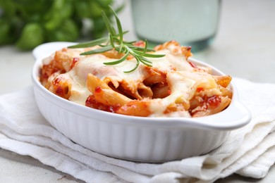 Photo of Delicious al forno pasta in baking dish on light table, closeup