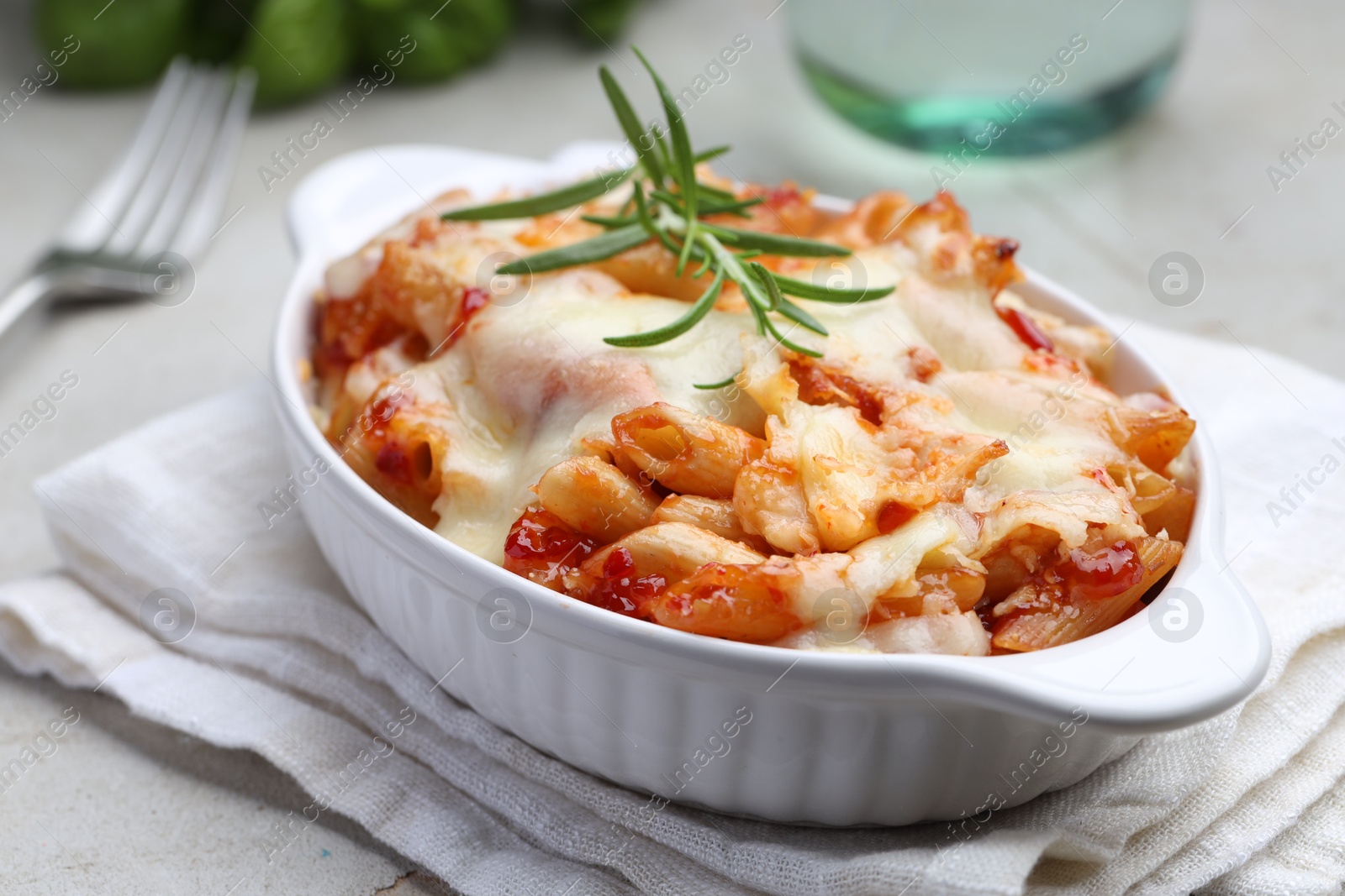 Photo of Delicious al forno pasta in baking dish on light table, closeup