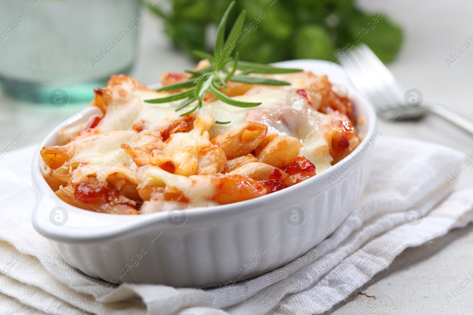 Photo of Delicious al forno pasta in baking dish on light table, closeup