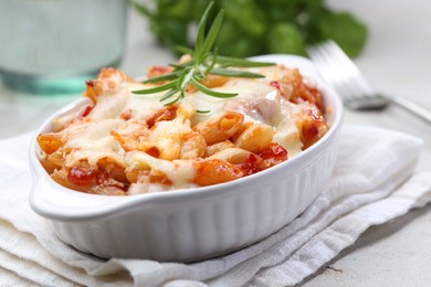 Photo of Delicious al forno pasta in baking dish on light table, closeup