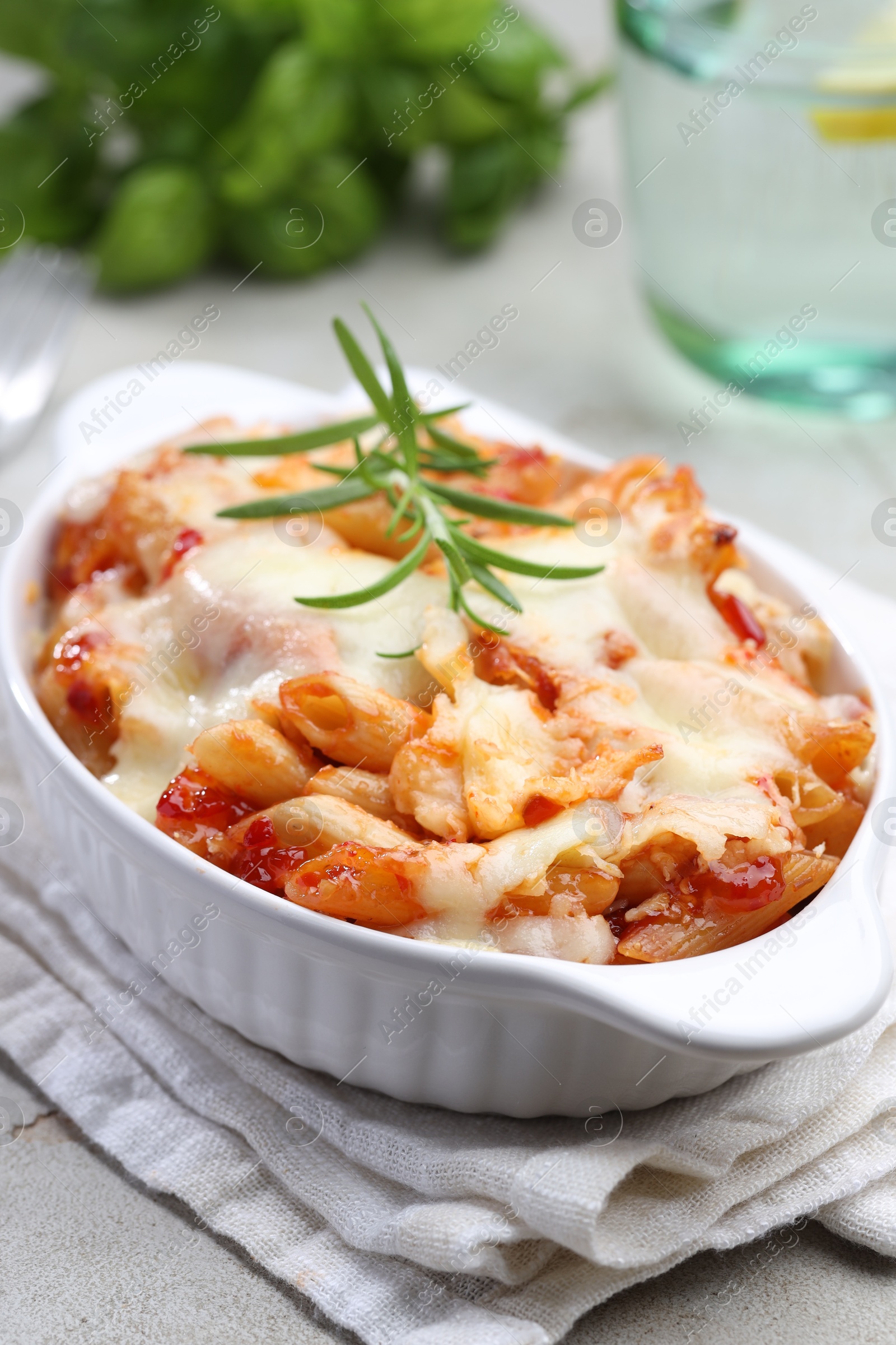 Photo of Delicious al forno pasta in baking dish on light table, closeup