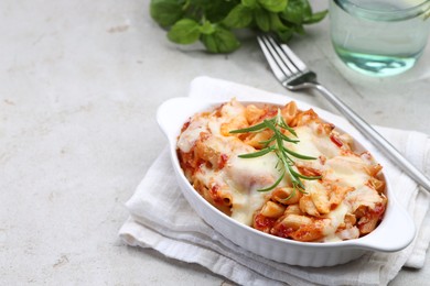 Photo of Delicious al forno pasta in baking dish on light table. Space for text