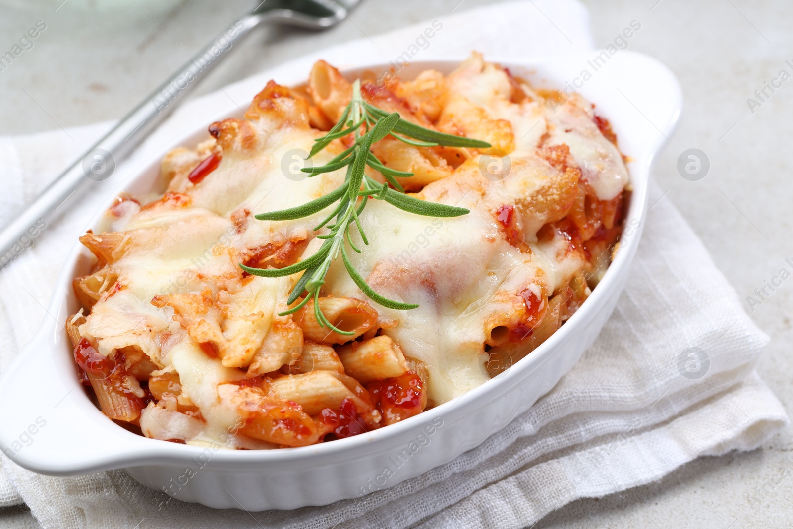 Photo of Delicious al forno pasta in baking dish on light table, closeup