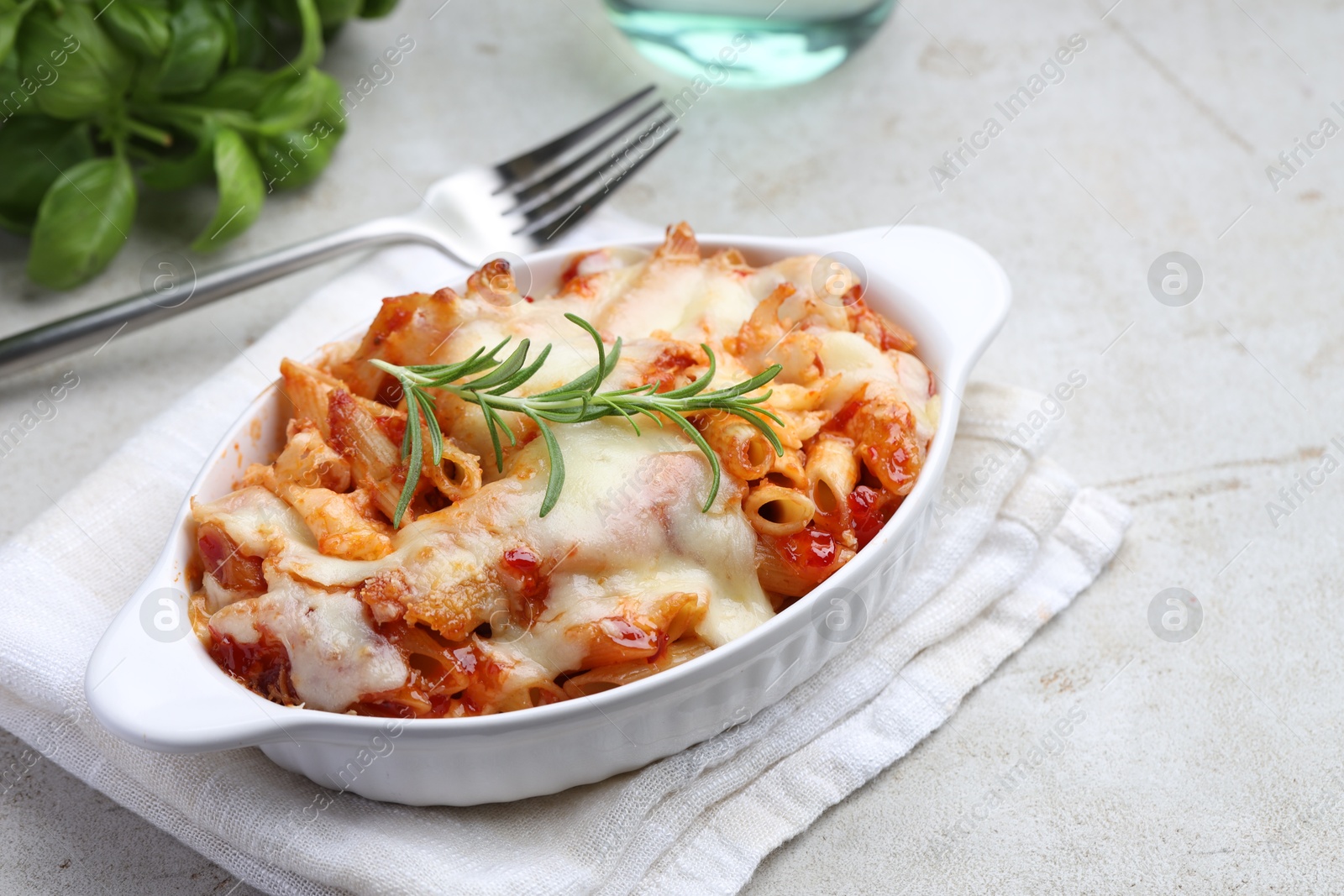 Photo of Delicious al forno pasta in baking dish on light table, closeup