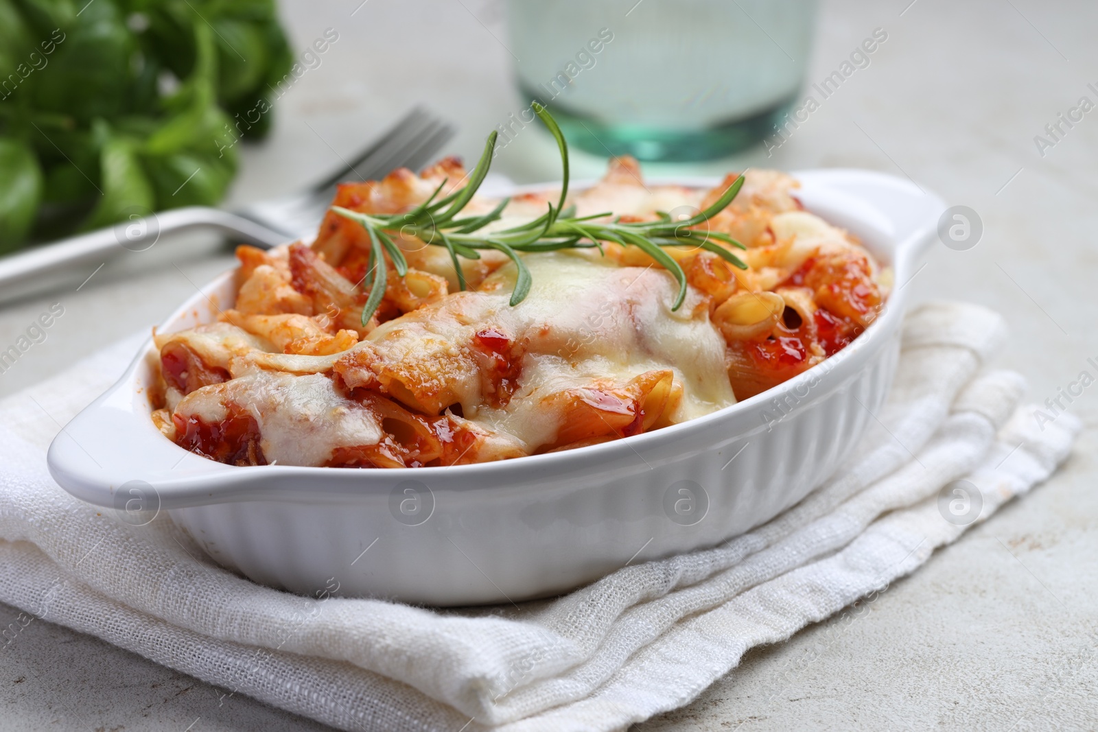 Photo of Delicious al forno pasta in baking dish on light table, closeup