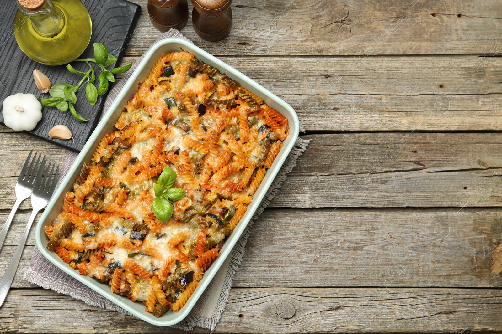 Photo of Delicious al forno pasta in baking dish on wooden table, flat lay. Space for text