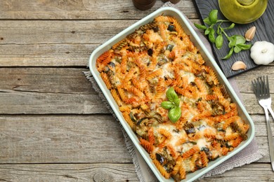 Photo of Delicious al forno pasta in baking dish on wooden table, flat lay. Space for text