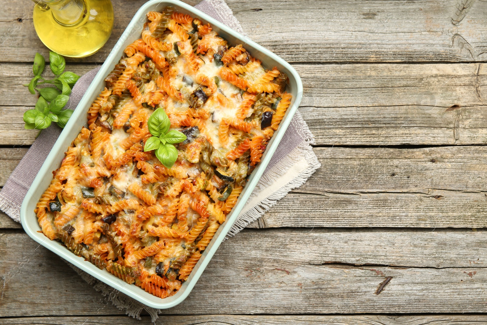 Photo of Delicious al forno pasta in baking dish on wooden table, top view. Space for text