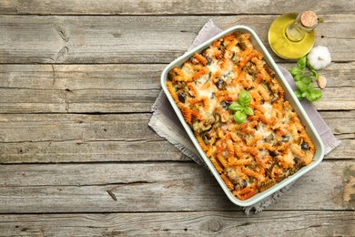 Photo of Delicious al forno pasta in baking dish on wooden table, top view. Space for text