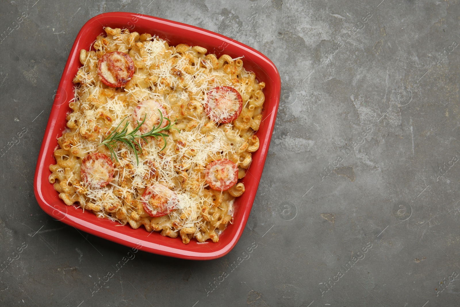 Photo of Delicious al forno pasta in baking dish on grey table, top view. Space for text