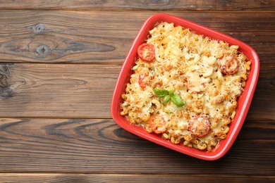 Photo of Delicious al forno pasta in baking dish on wooden table, top view. Space for text