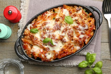 Photo of Delicious al forno pasta in baking dish on wooden table, flat lay