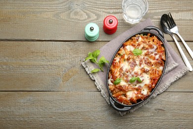 Photo of Delicious al forno pasta in baking dish on wooden table, flat lay. Space for text