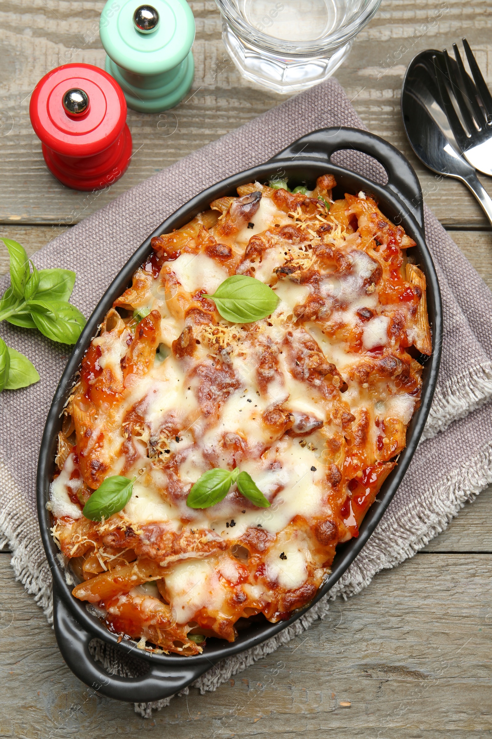 Photo of Delicious al forno pasta in baking dish on wooden table, flat lay