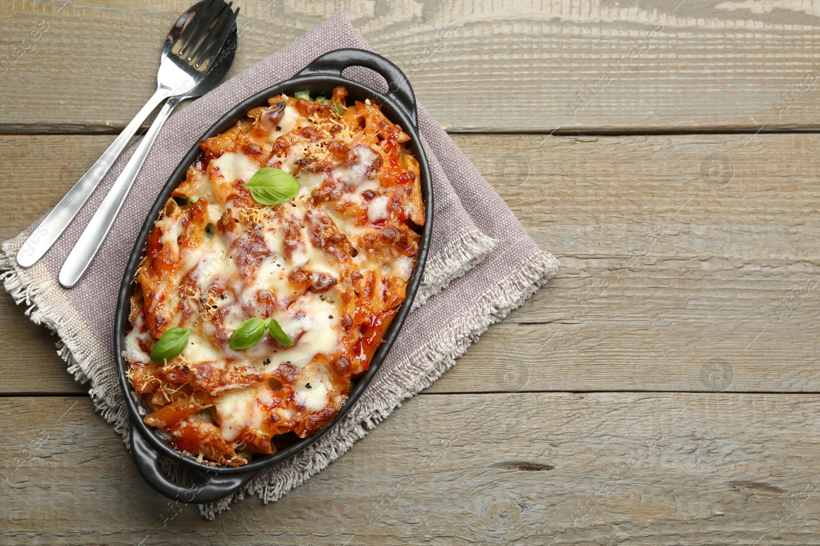 Photo of Delicious al forno pasta in baking dish on wooden table, top view. Space for text