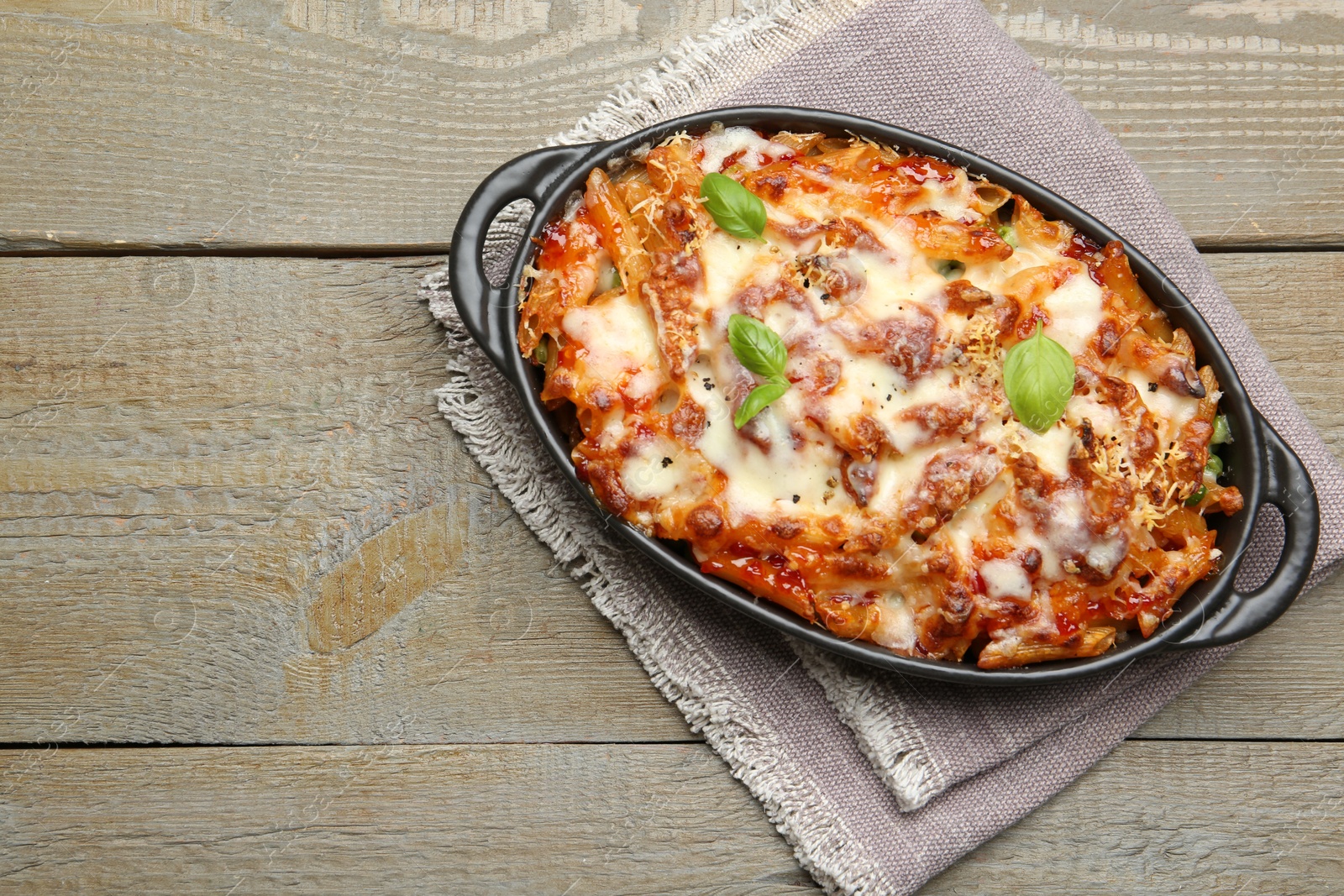 Photo of Delicious al forno pasta in baking dish on wooden table, top view. Space for text