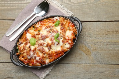 Photo of Delicious al forno pasta in baking dish on wooden table, top view. Space for text