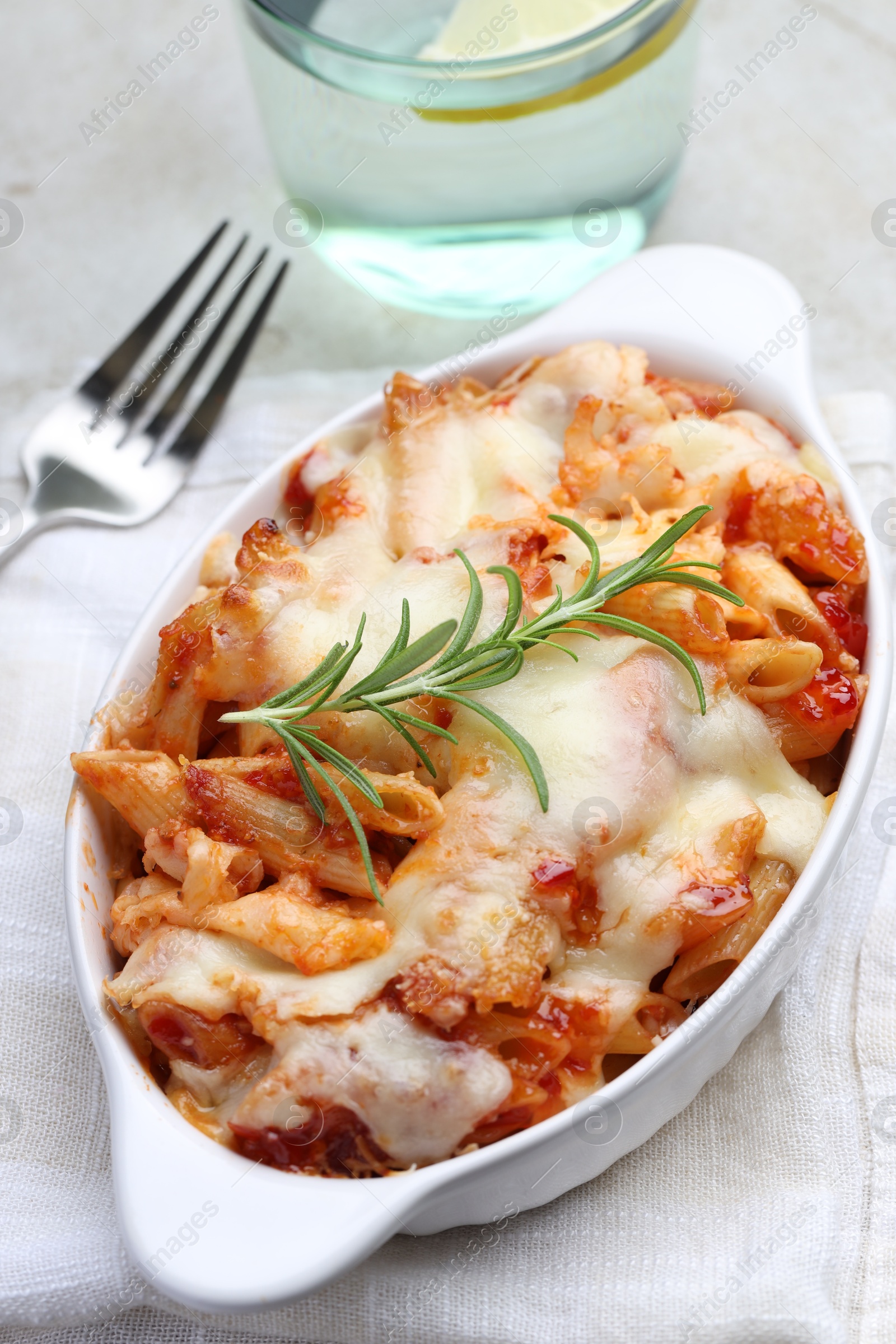 Photo of Delicious al forno pasta in baking dish on light table, closeup