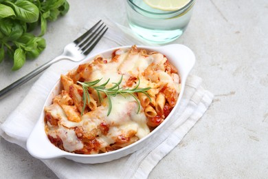 Photo of Delicious al forno pasta in baking dish on light table, closeup