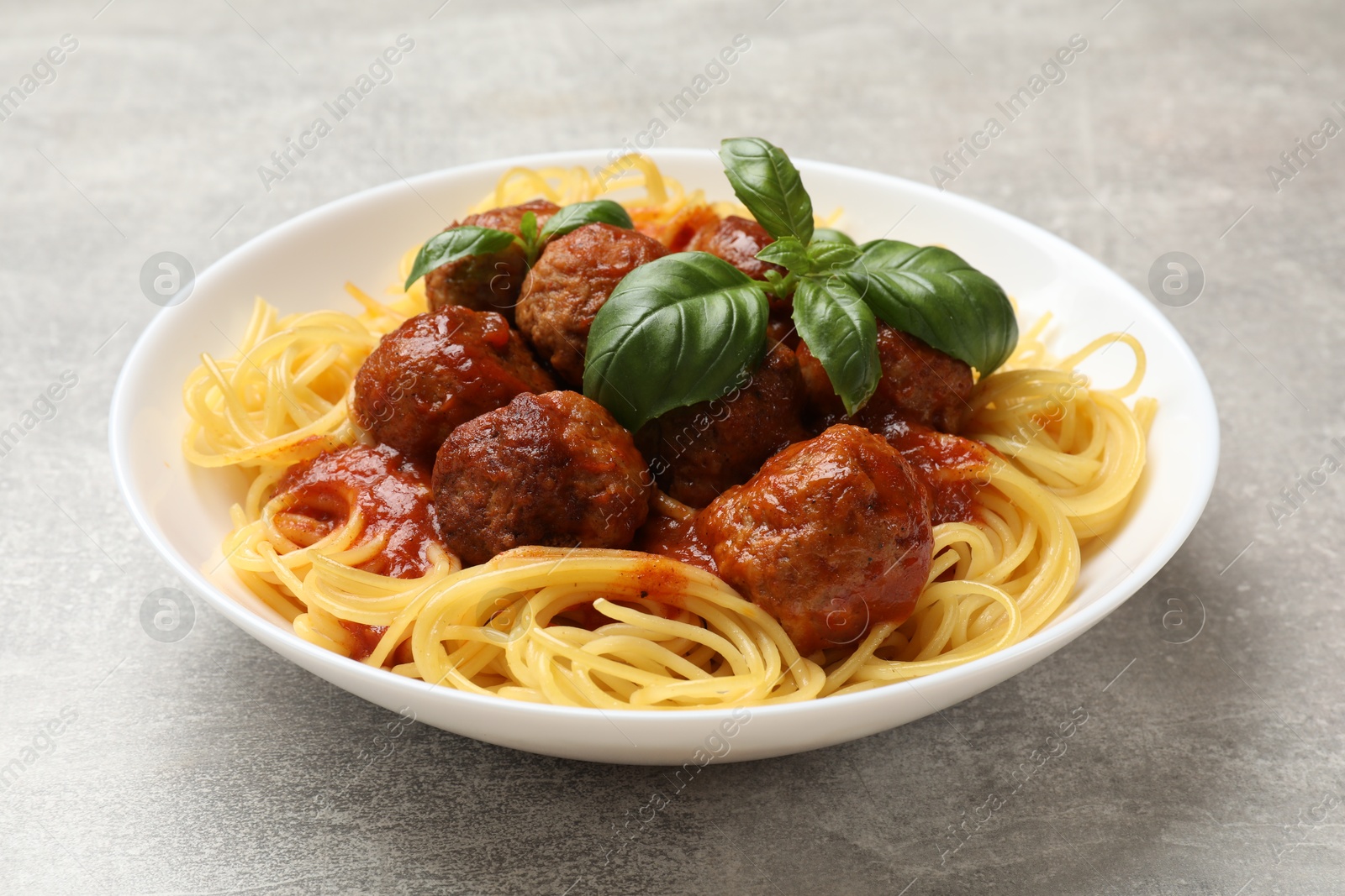 Photo of Delicious pasta with meatballs on grey table, closeup