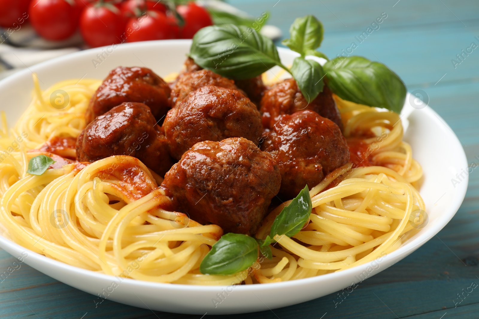 Photo of Delicious pasta with meatballs on blue wooden table, closeup