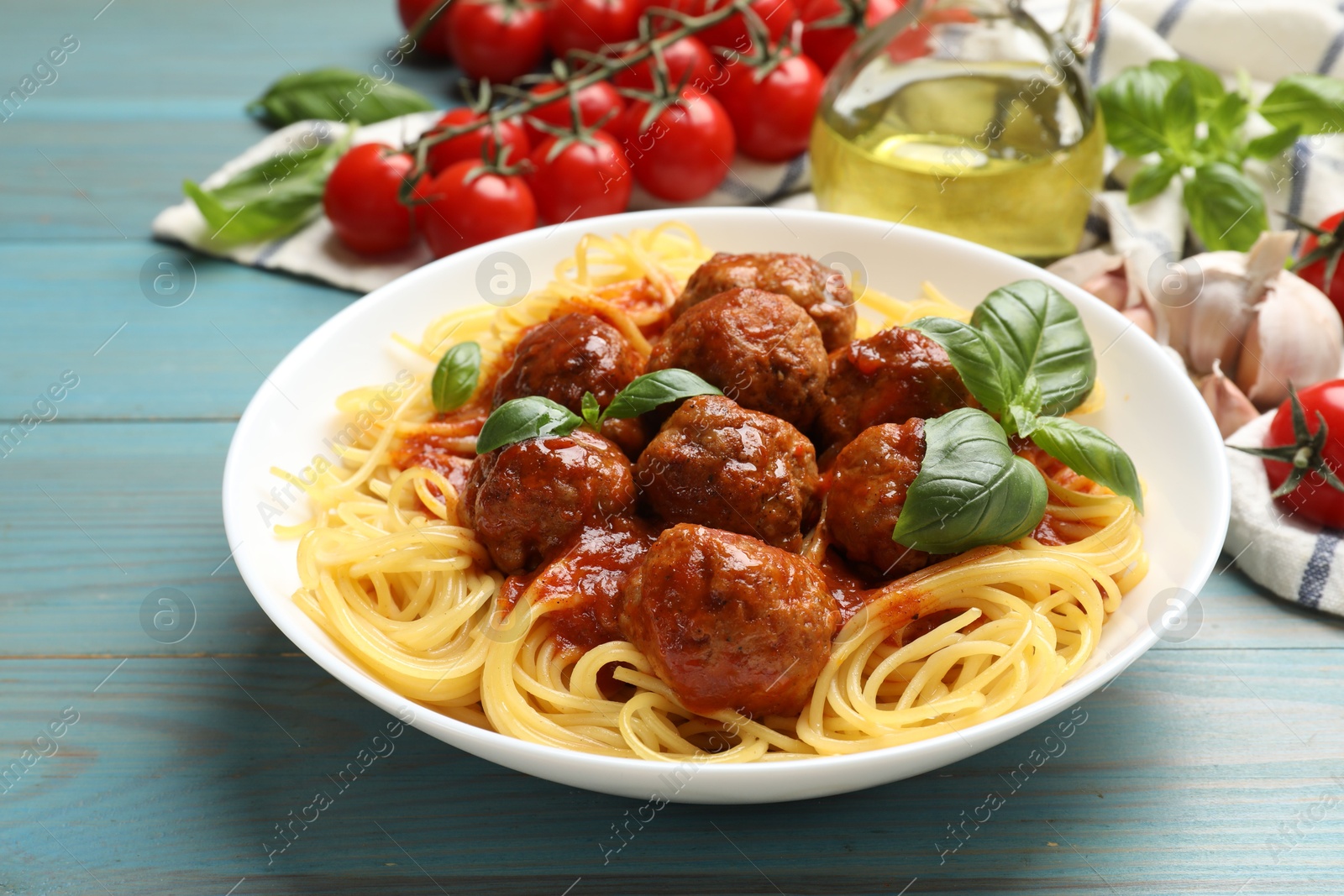 Photo of Delicious pasta with meatballs and ingredients on blue wooden table, closeup