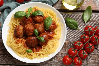 Delicious pasta with meatballs and ingredients on wooden table, flat lay