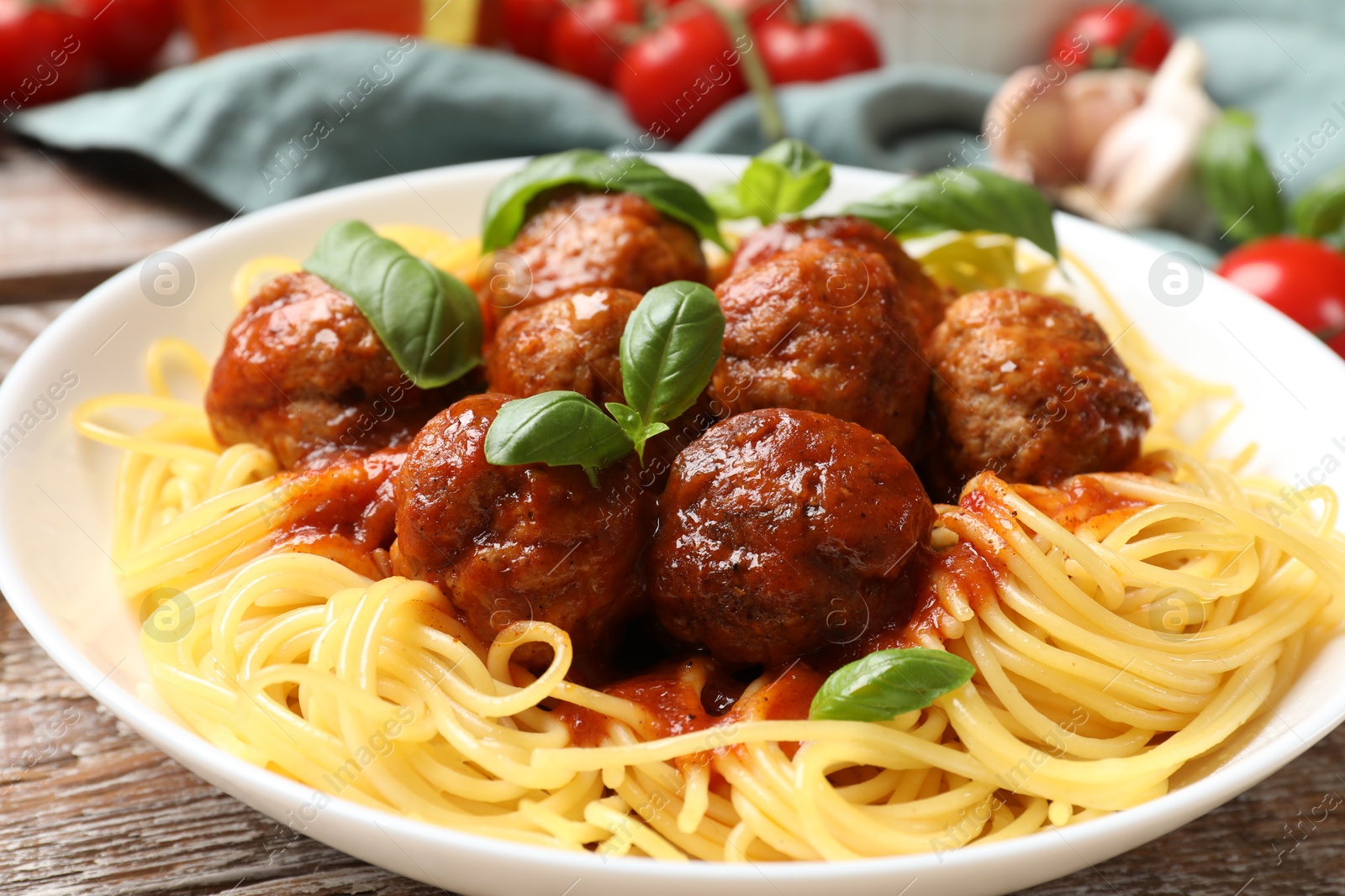 Photo of Delicious pasta with meatballs and ingredients on wooden table, closeup