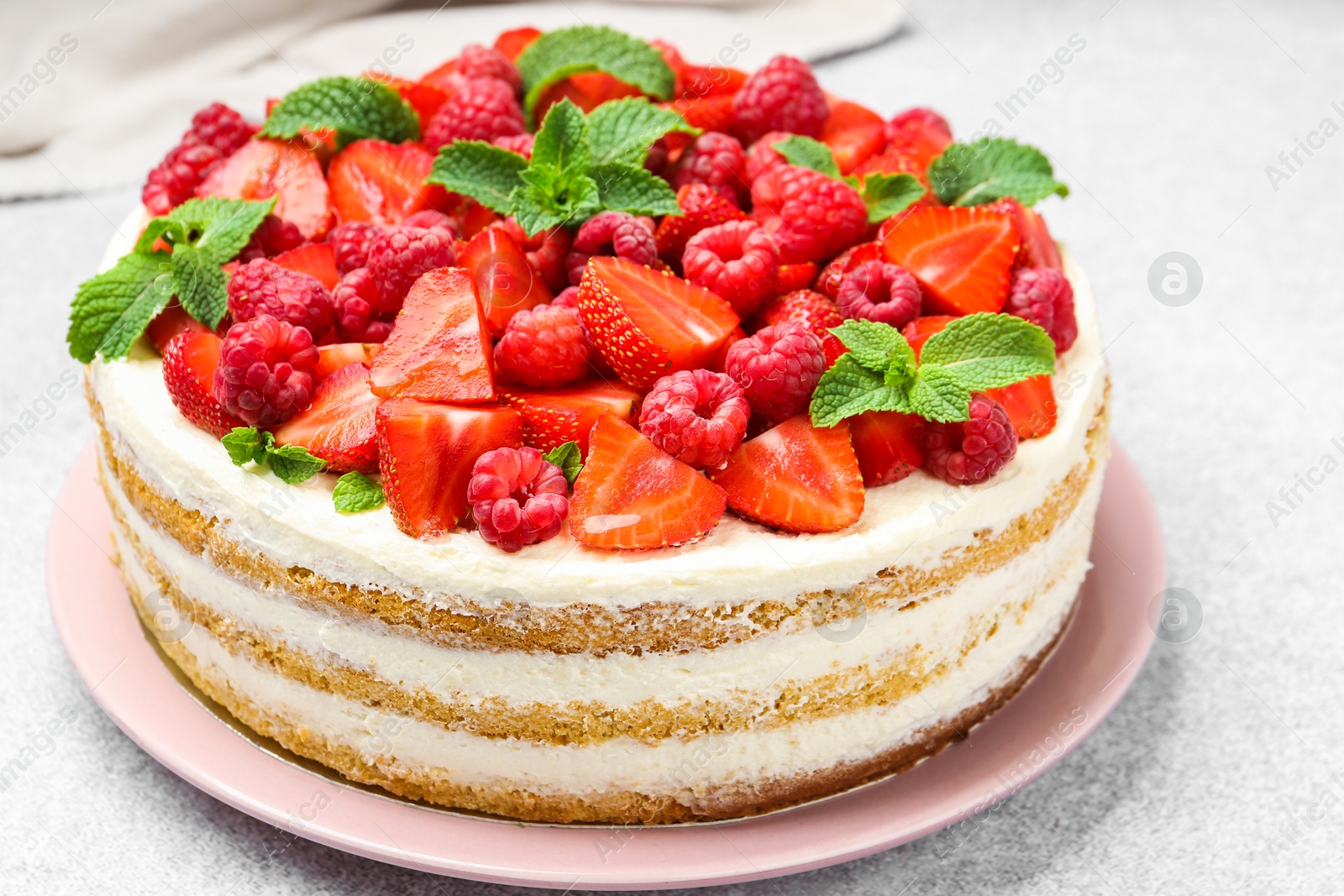 Photo of Tasty sponge cake with fresh berries and mint on light gray table, closeup