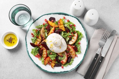 Plate with fresh burrata salad served on grey textured table, flat lay