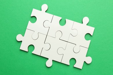 White puzzle pieces on green background, top view