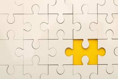 Photo of White puzzle with missing piece on yellow background, top view