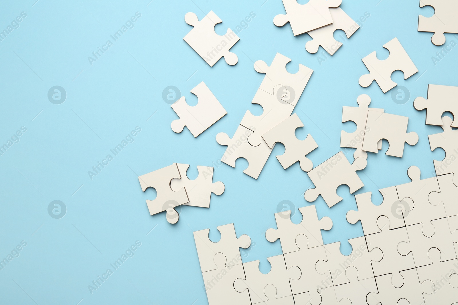 Photo of White puzzle pieces on light blue background, top view