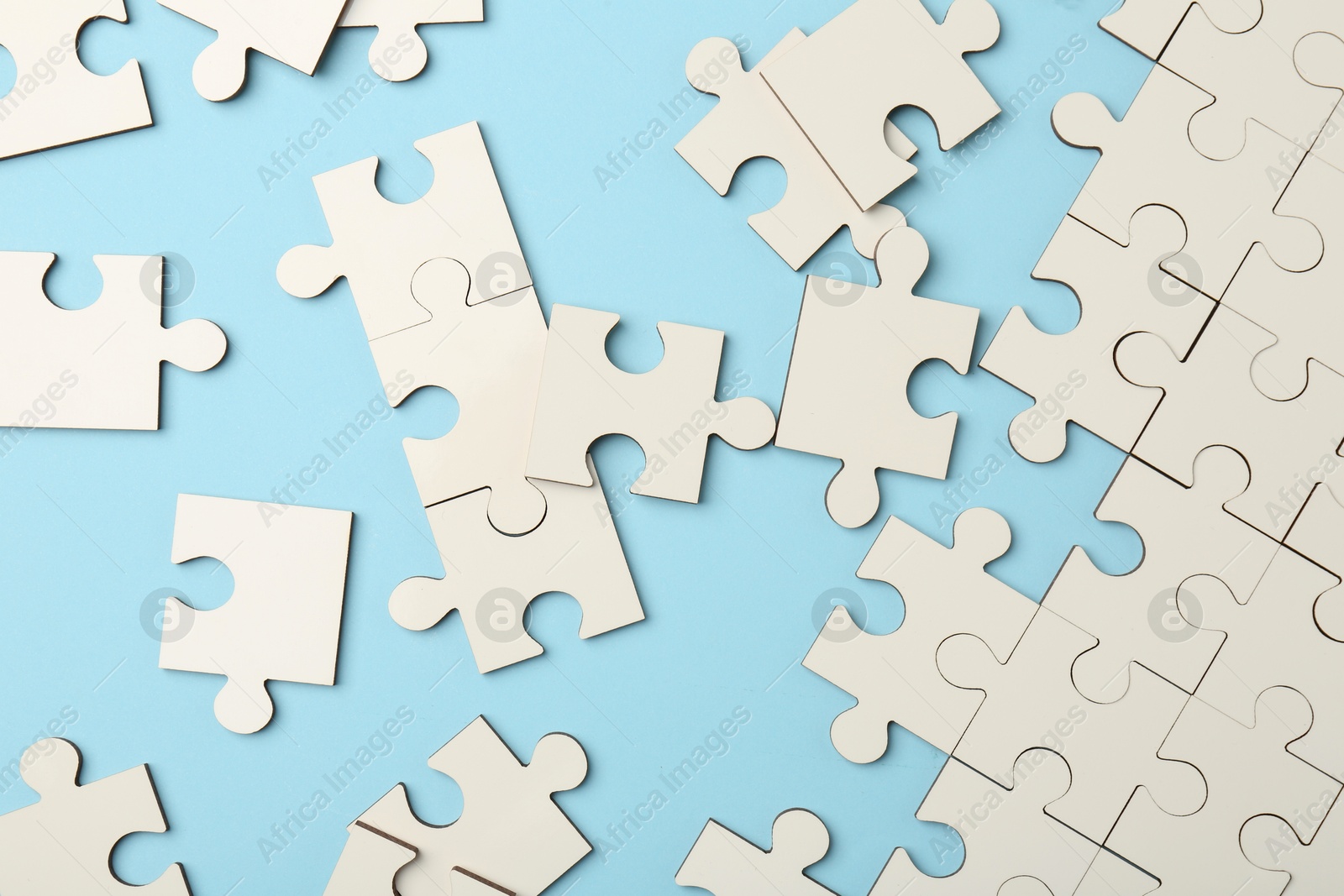 Photo of White puzzle pieces on light blue background, top view