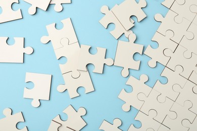 White puzzle pieces on light blue background, top view