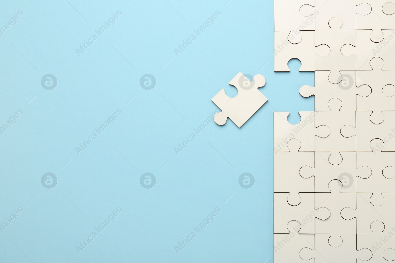 Photo of White puzzle pieces on light blue background, top view. Space for text