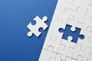 Photo of White puzzle pieces on blue background, top view