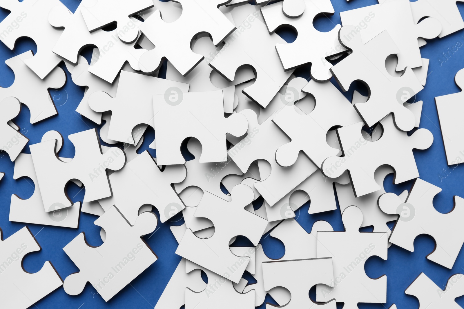 Photo of White puzzle pieces on blue background, top view