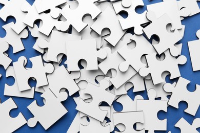 Photo of White puzzle pieces on blue background, top view