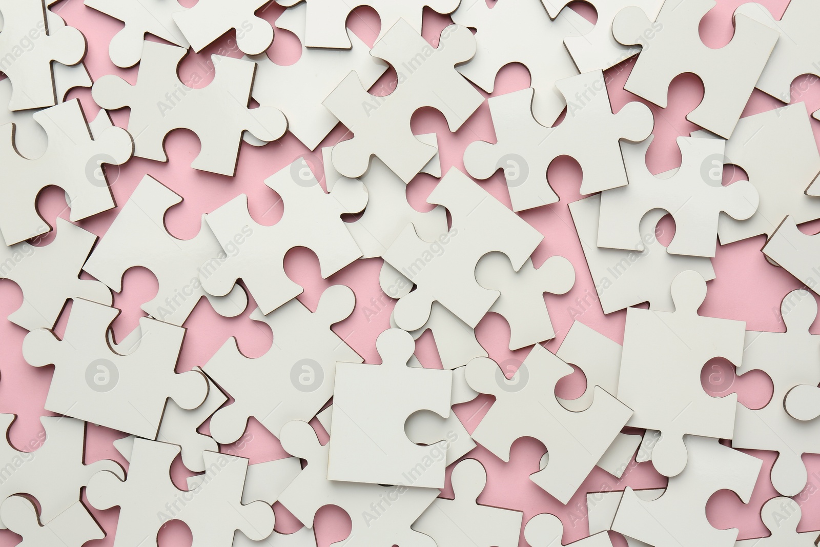 Photo of White puzzle pieces on pink background, top view